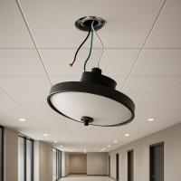 A large black and white light fixture with exposed wires, suspended from the ceiling of a long hallway in an office complex.